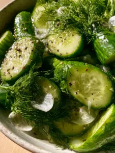 Macro shot of garlic dill cucumbers showing translucent garlic slices and feathery dill clusters with wet brine highlights.