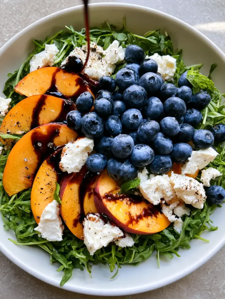 Top-down view of Blueberry Peach Feta Salad with feta crumbles and mint garnish.