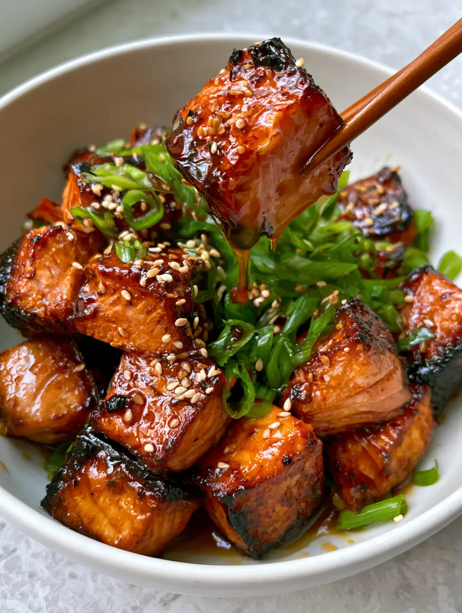 Top-down view of honey garlic salmon bites with visible charred crispy edges and a thick amber glaze. (honey garlic salmon bites)